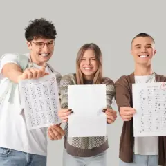 Tres estudiantes sonríen mostrando sus hojas de respuestas con puntuaciones aptis de A+.