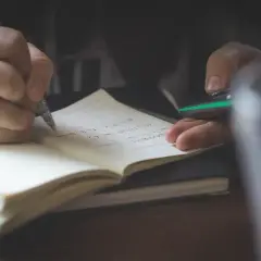 Mano escribiendo en un cuaderno. Quizás anotando **palabras homógrafas** para un estudio.