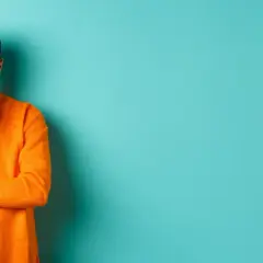 Hombre con suéter naranja, pensativo, reflexionando sobre la diferencia entre fun y funny.