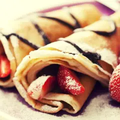 Cremosas crepas rellenas de fresas y bañadas en chocolate, perfectas para celebrar el pancake day. Espolvoreadas con azúcar glas.