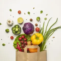 Bolsa de papel llena de verduras frescas: brócoli, col morada, pimientos, cebolletas, tomates, chiles, ajo, limón y una naranja. ¡Perfecto para 100 comidas!