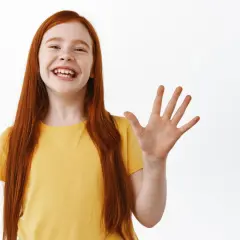 Niña pelirroja sonriente saluda con la mano, ¡how are ya!