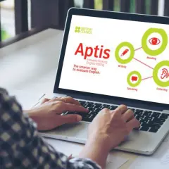Persona usa laptop con pantalla que muestra el logo de British Council y el concepto de **Aptis**, un examen de inglés que evalúa lectura, escritura, escucha y habla.