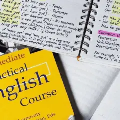 Cuaderno con apuntes de inglés sobre "have got", un libro de texto "Practical English Course" y un ejemplo de posesión: "He has got a red car".