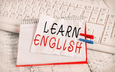 Cuaderno con "LEARN ENGLISH" escrito a mano, sobre un teclado. Una lista de palabras en inglés para aprender.