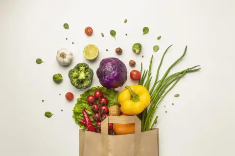 Bolsa de papel llena de verduras frescas: brócoli, col morada, pimientos, cebolletas, tomates, chiles, ajo, limón y una naranja. ¡Perfecto para 100 comidas!
