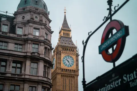 Edificio histórico y el Big Ben, un icono de los festivos UK, junto a un cartel del metro de Londres.