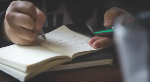 Mano escribiendo en un cuaderno. Quizás anotando **palabras homógrafas** para un estudio.