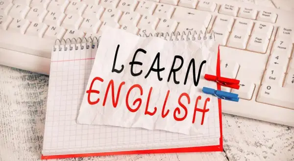 Cuaderno con "LEARN ENGLISH" escrito a mano, sobre un teclado. Una lista de palabras en inglés para aprender.