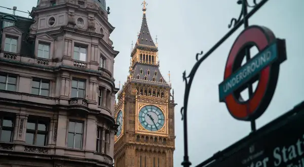 Edificio histórico y el Big Ben, un icono de los festivos UK, junto a un cartel del metro de Londres.