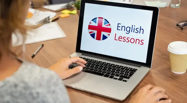 Persona aprende inglés en línea. La pantalla muestra "English Lessons" y la bandera del Reino Unido.