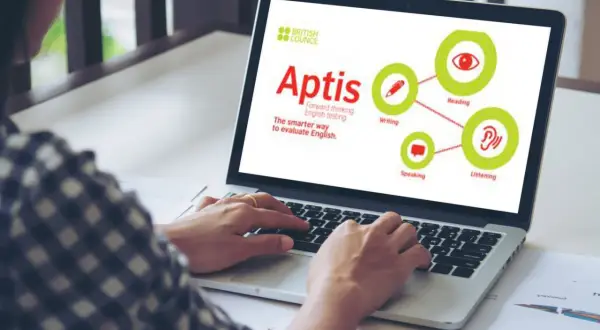 Persona usa laptop con pantalla que muestra el logo de British Council y el concepto de **Aptis**, un examen de inglés que evalúa lectura, escritura, escucha y habla.