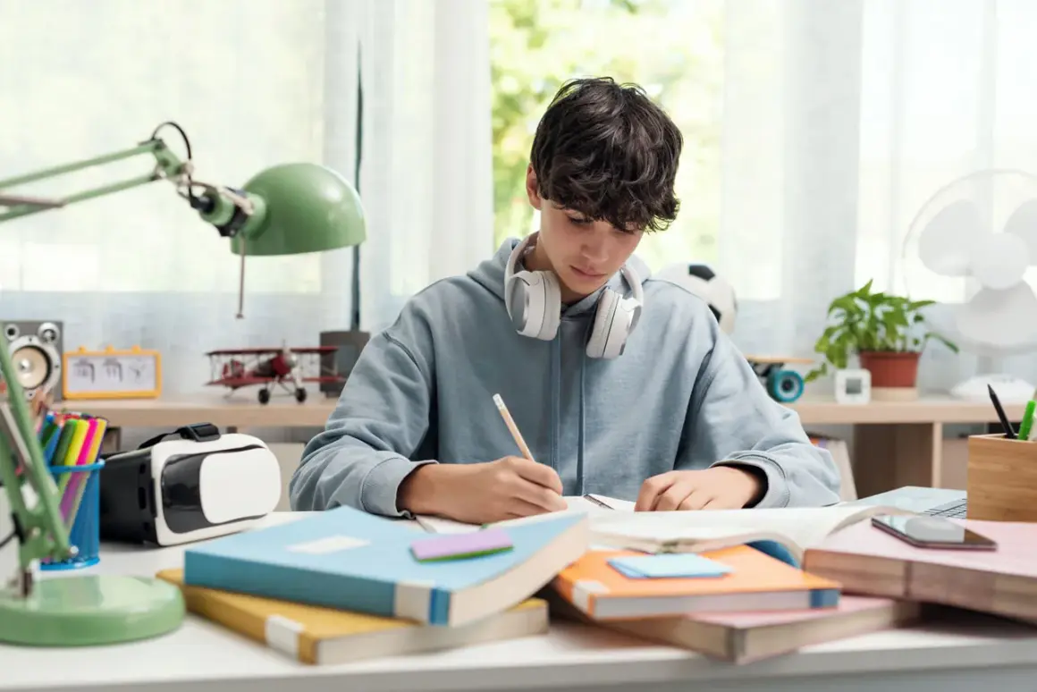 Un chico con auriculares se concentra en sus estudios, rodeado de libros y un casco de RV. ¡Yo también!