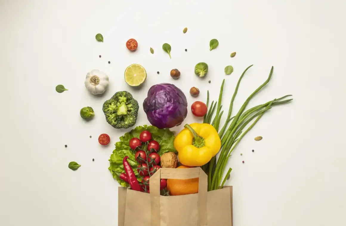 Bolsa de papel llena de verduras frescas: brócoli, col morada, pimientos, cebolletas, tomates, chiles, ajo, limón y una naranja. ¡Perfecto para 100 comidas!