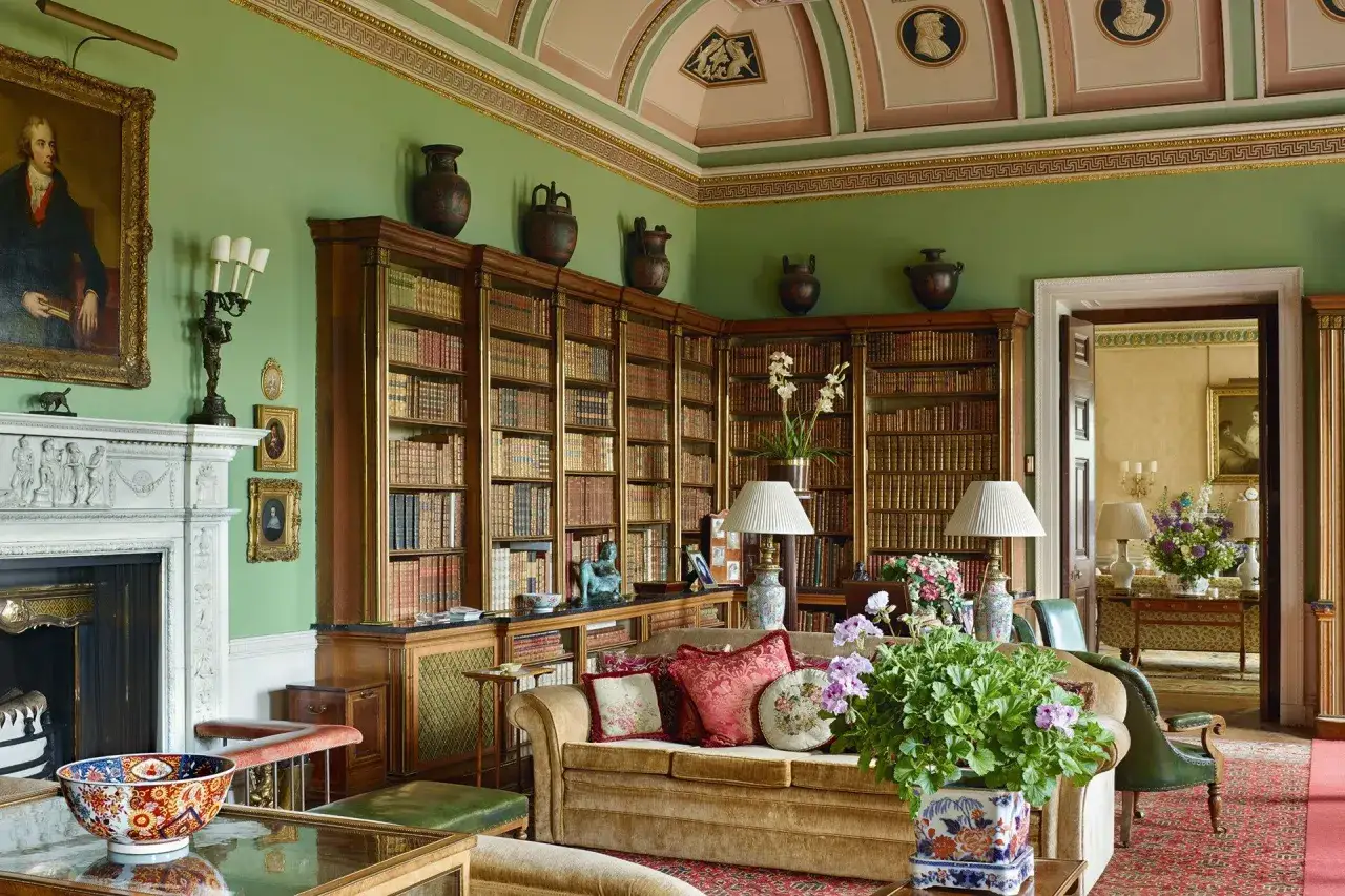 Biblioteca de una casa típica inglesa, con sofás, chimenea y estanterías repletas de libros.