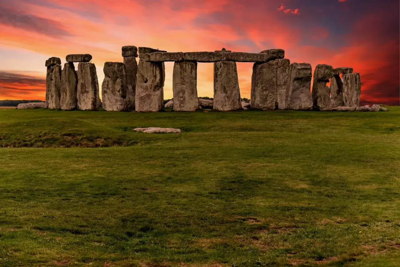 El icónico Stonehenge en Inglaterra, con sus imponentes piedras bajo un cielo crepuscular de tonos rojizos y anaranjados.