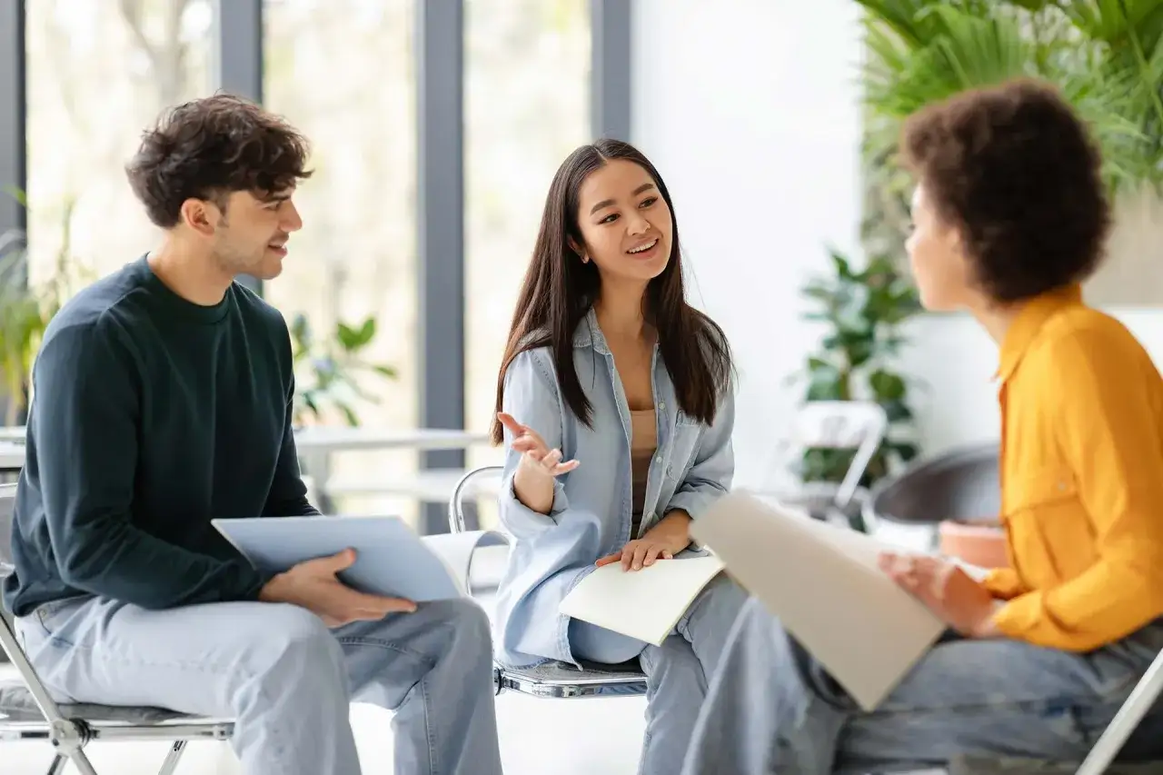 Tres j&oacute;venes participan en conversaciones en ingl&eacute;s B1, compartiendo ideas y aprendiendo juntos en un ambiente relajado.