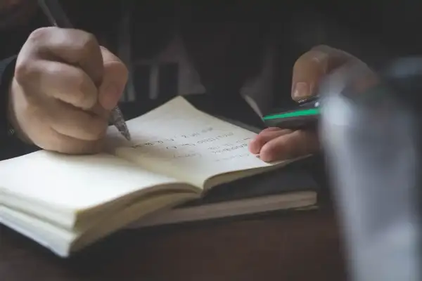 Mano escribiendo en un cuaderno. Quizás anotando **palabras homógrafas** para un estudio.