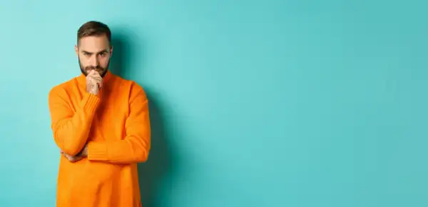 Hombre con suéter naranja, pensativo, reflexionando sobre la diferencia entre fun y funny.
