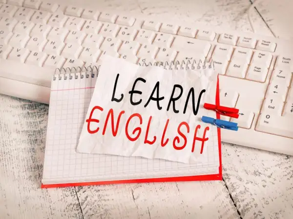 Cuaderno con "LEARN ENGLISH" escrito a mano, sobre un teclado. Una lista de palabras en inglés para aprender.